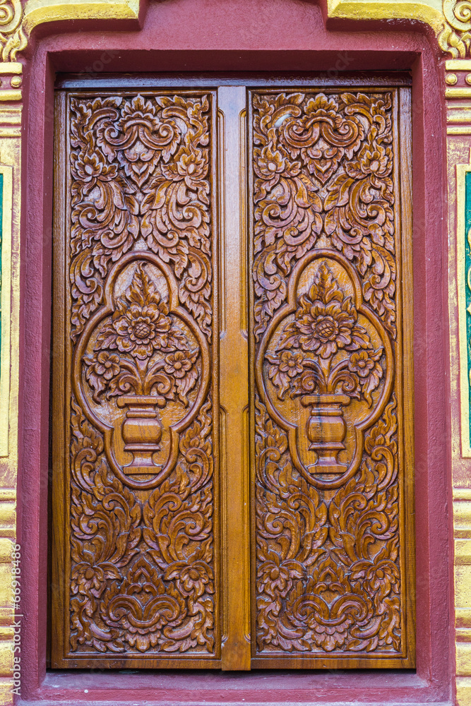 Richly decorated vintage wooden window in the wall of the temple