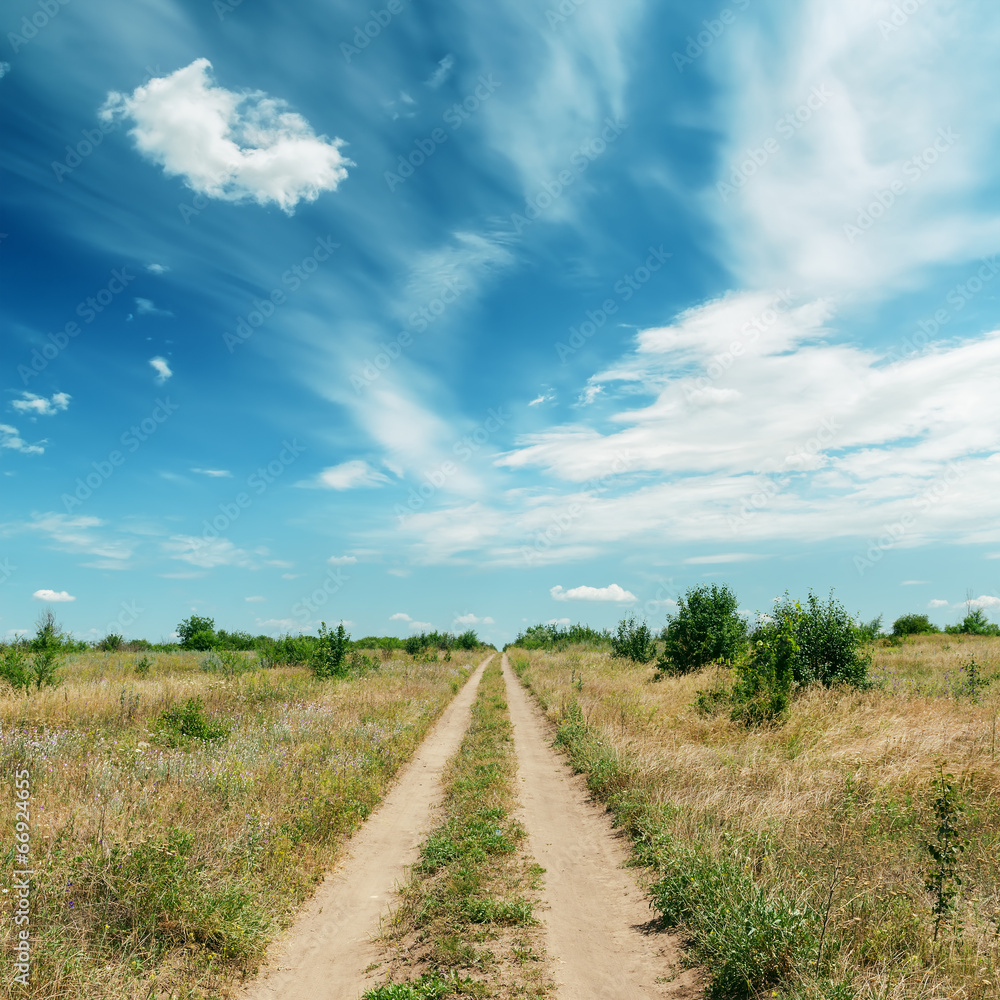 rural road in green landscape and dramatic blue sky with clouds rural road in green landscape and dramatic blue sky with clouds
