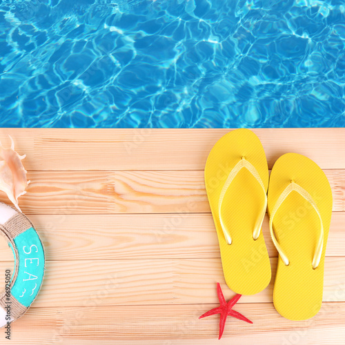 Colored flip flops on wooden platform beside sea