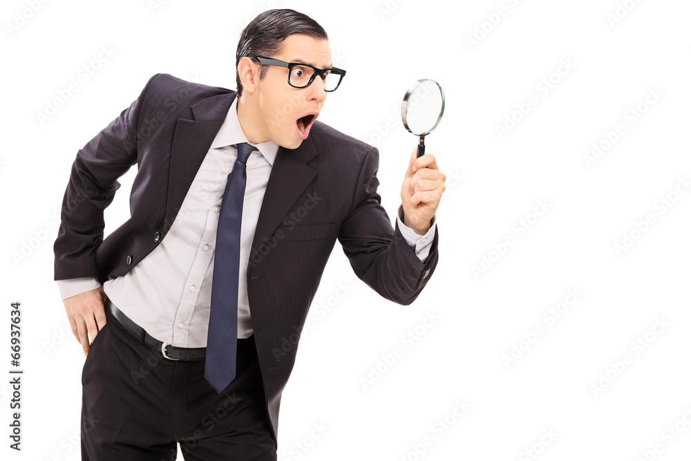 Shocked businessman looking through a magnifier Shocked businessman looking through a magnifier