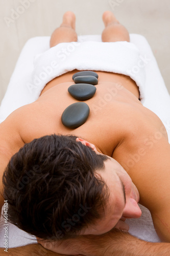 Young man receiving hot stone treatment