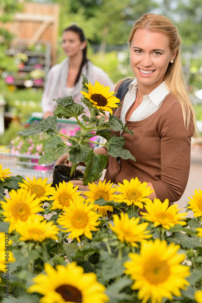 Fototapeta premium Smiling customer woman shopping for potted sunflower