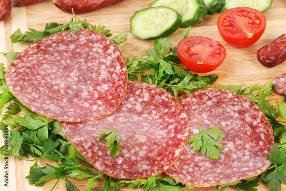 Sausage salami and vegetables on wooden platter. Sausage salami and vegetables on wooden platter.