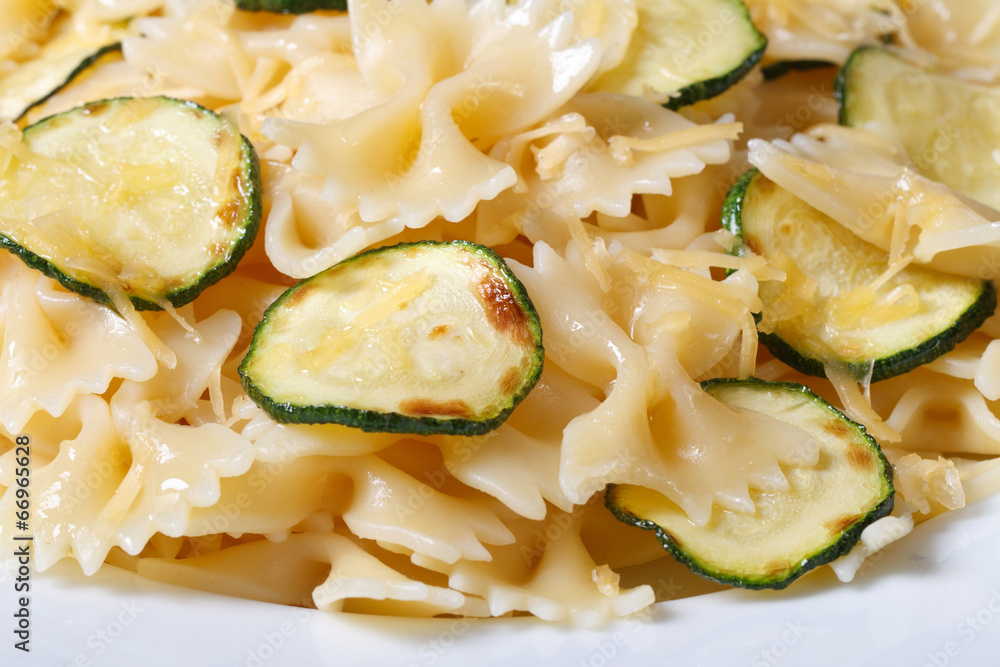 Farfalle pasta with zucchini and cheese on a white plate macro Farfalle pasta with zucchini and cheese on a white plate macro