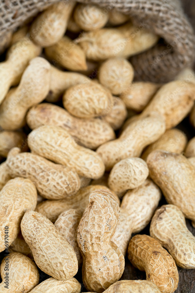 peanuts in a miniature burlap bag on wooden surface peanuts in a miniature burlap bag on wooden surface