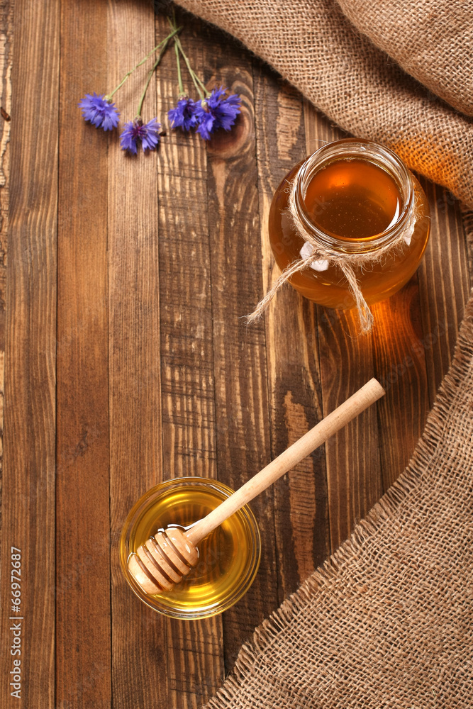 honey in a glass bowl on a wooden boards background