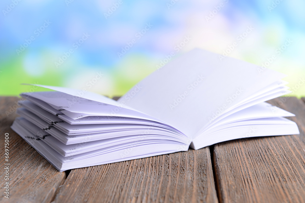 Open white book on wooden table on bright background Open white book on wooden table on bright background
