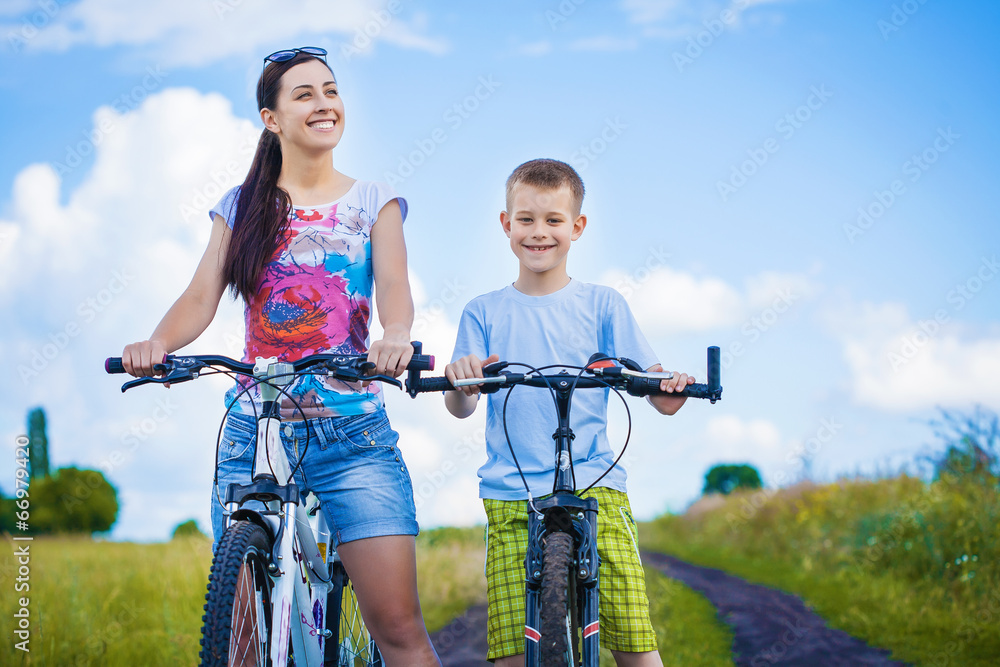 Obraz premium happy mother and son riding bicycle in the field