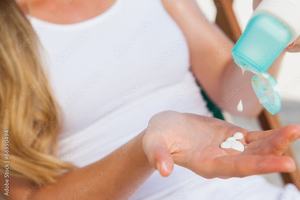 Naklejka premium Woman putting sunblock on her hand at the beach