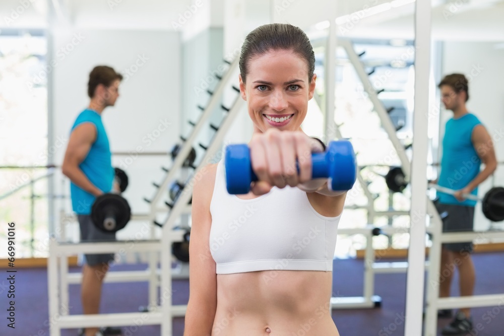 Fit brunette exercising with blue dumbbells Fit brunette exercising with blue dumbbells