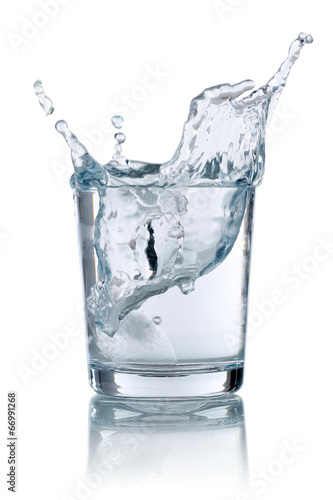 Eiswürfel fällt in ein Glas mit Wasser