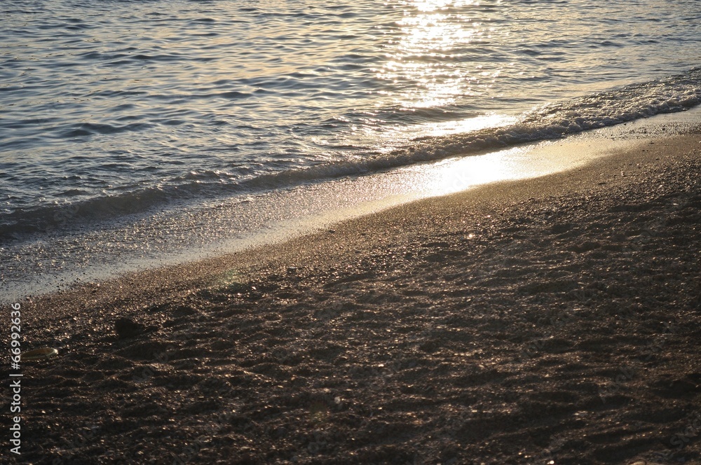 Evening waves on the beach with glistening sea