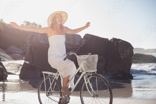 Beautiful blonde in white sundress on bike ride at the beach