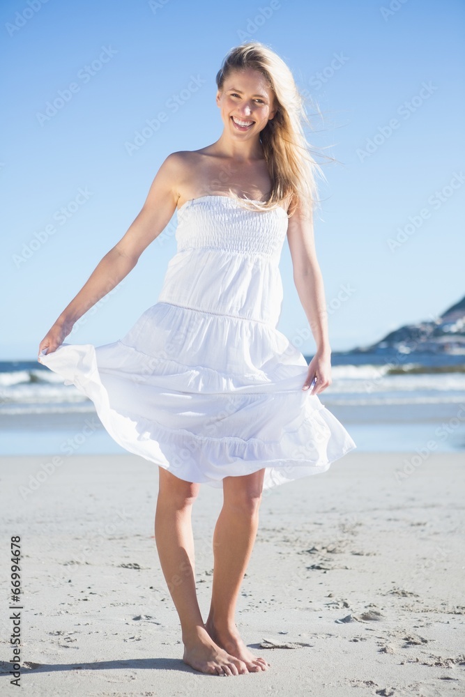 Woman in white dress smiling at camera on the beach Woman in white dress smiling at camera on the beach