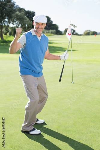 Happy golfer cheering on putting green at eighteenth hole