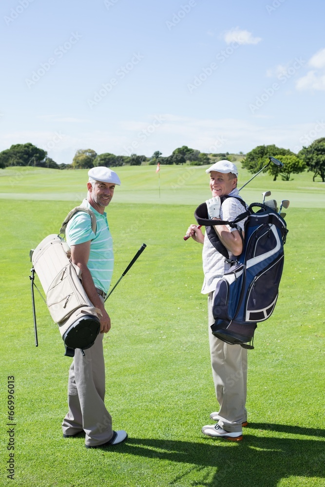 Obraz premium Golfer friends smiling at camera holding their golf bags