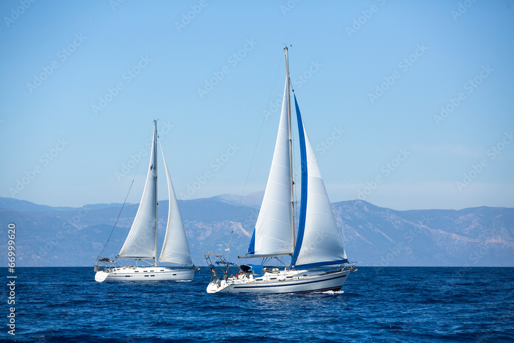 Group of sail yachts in regatta near a coast.