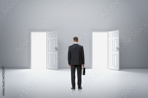Backview portrait of businessman in front of two doors
