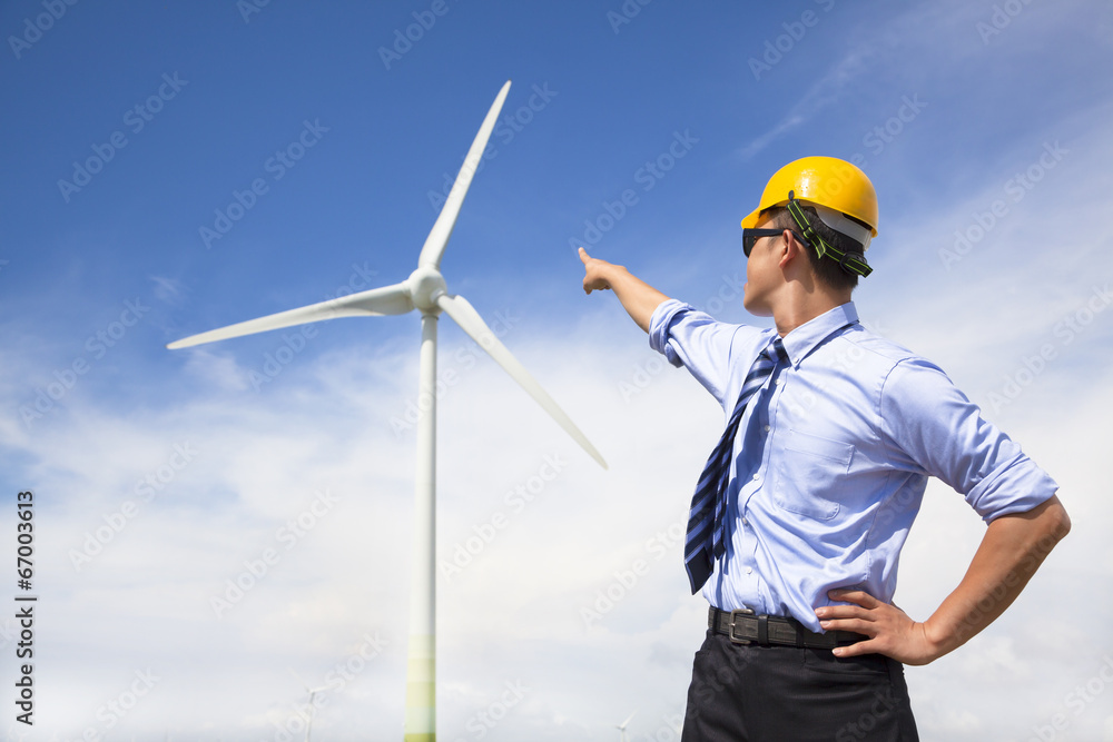 young engineer standing and point to wind generator young engineer standing and point to wind generator