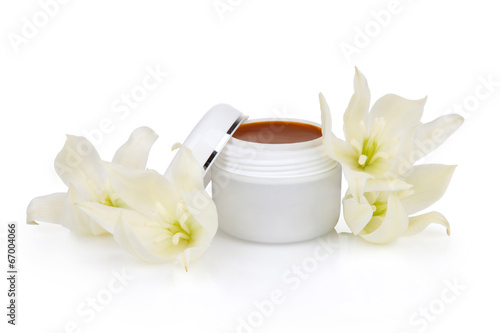 Open jar with the cosmetic cream and flowers