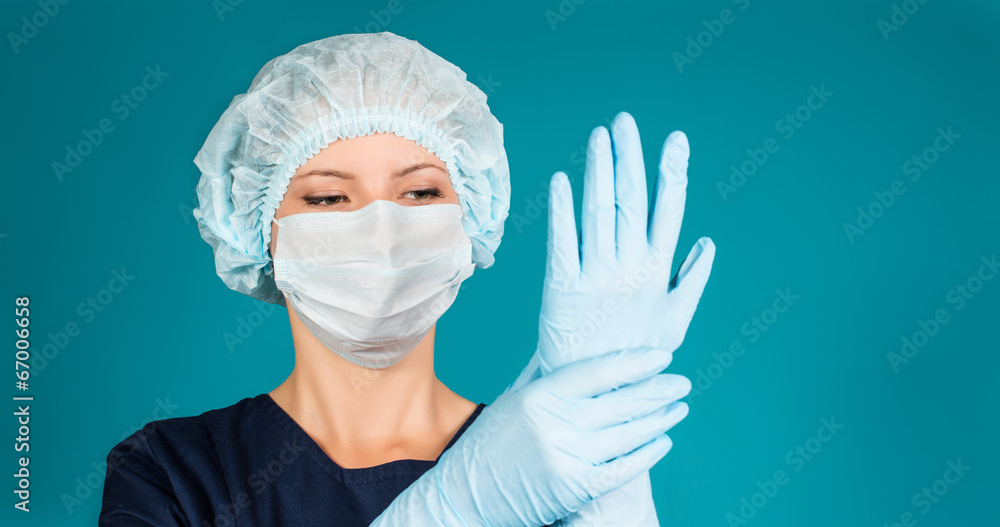 Doctor or nurse wearing surgical mask, cap and putting gloves. Stock Photo  | Adobe Stock