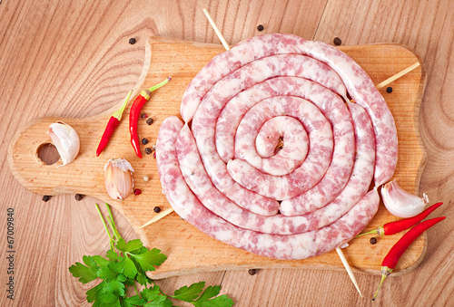 Fresh raw sausage on wooden background photo