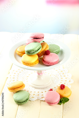 Gentle macaroons in vase on table on light background