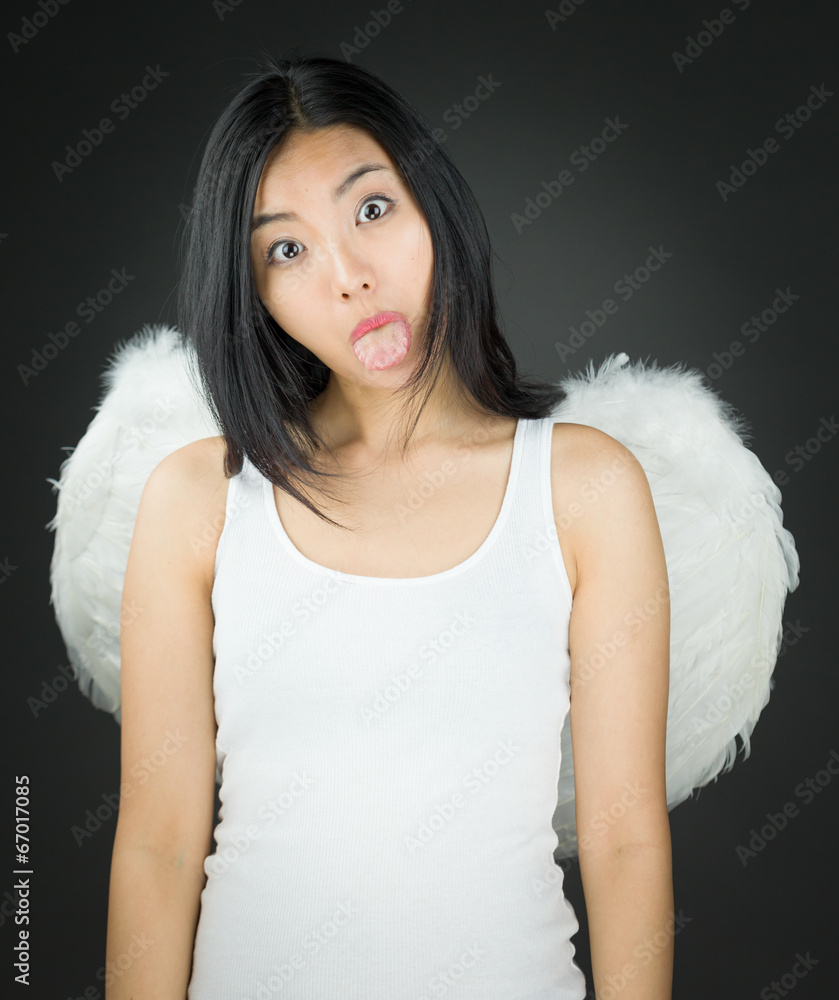 Asian young woman dressed up as an angel sticking out her tongue Asian young woman dressed up as an angel sticking out her tongue