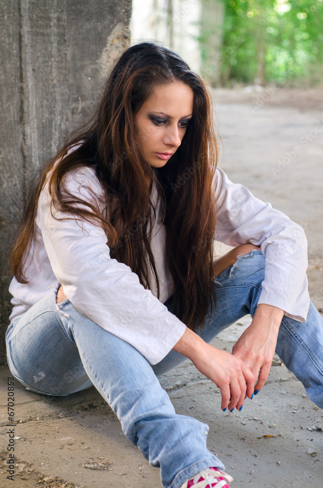 Obraz premium Depressed young girl sitting on the concrete floor
