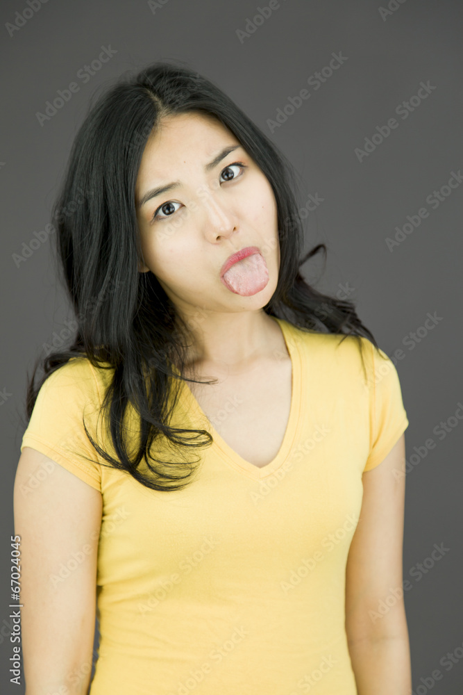 Asian young woman poking out tongue towards camera Asian young woman poking out tongue towards camera