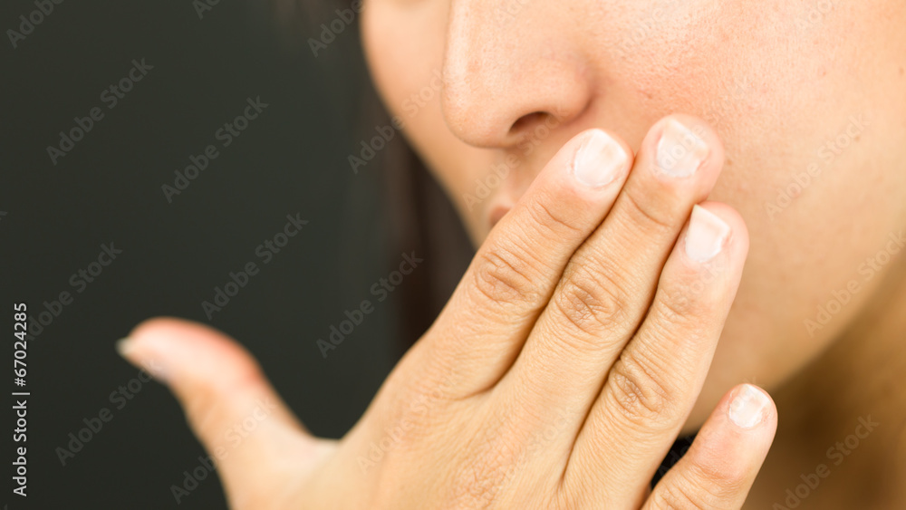 Extreme close-up of a young woman covering her mouth with her