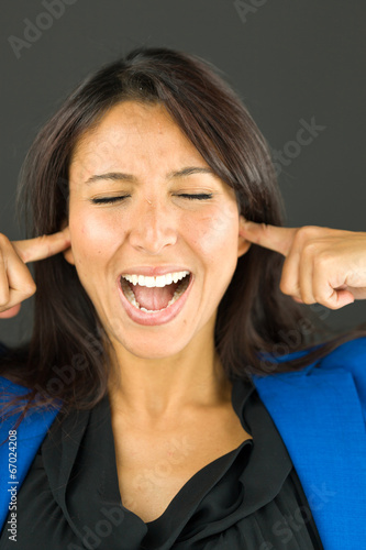 Frustrated young businesswoman shouting with her fingers in ears