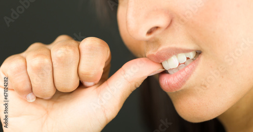Extreme close-up of a young woman biting her nails and smiling