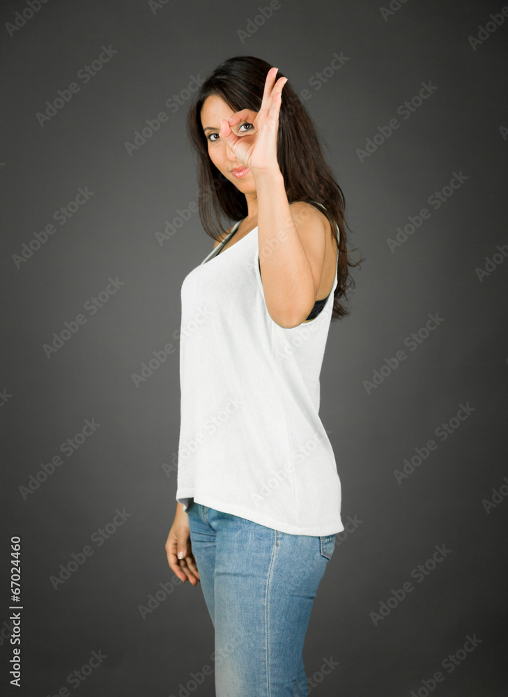 Side profile of a young woman looking through finger's hole Side profile of a young woman looking through finger's hole