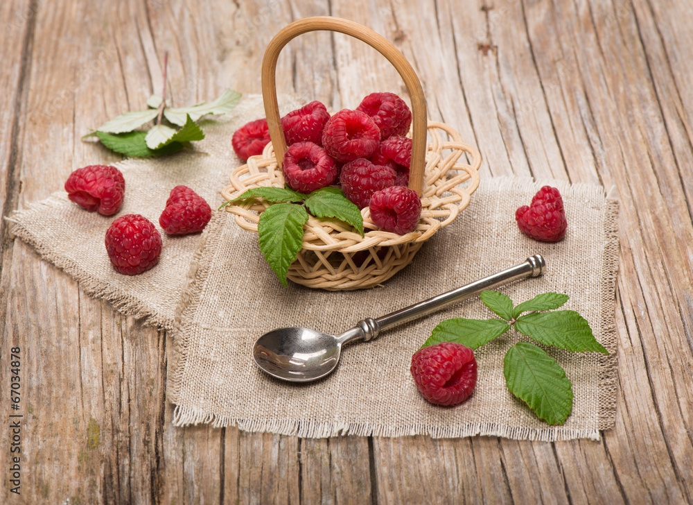 Sweet raspberries in basket  on the wooden table