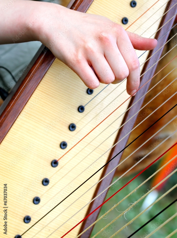 nice female hand while plucking the strings of a harp 2