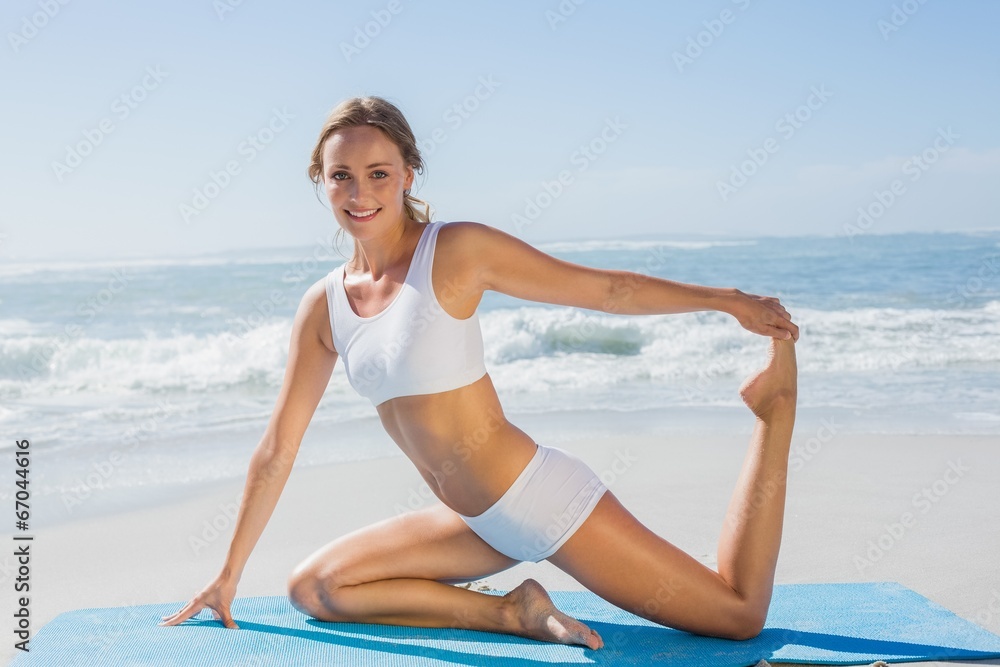 Gorgeous fit blonde in seated yoga pose on the beach