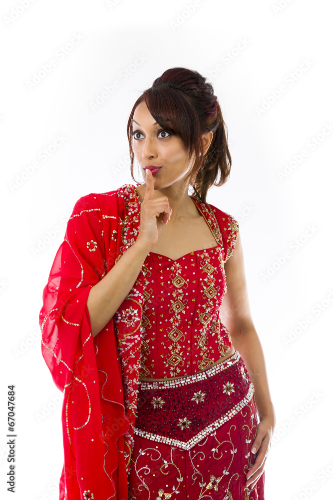 Young Indian woman standing with finger on lips Young Indian woman standing with finger on lips