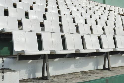 Rows of broken and stained white chairs in an outdoor auditorium