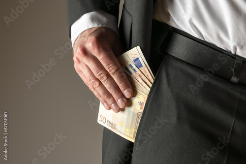 Businessman putting money in pocket photo