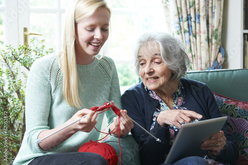 Grandmother With Digital Tablet Showing Granddaughter How To Kni photo