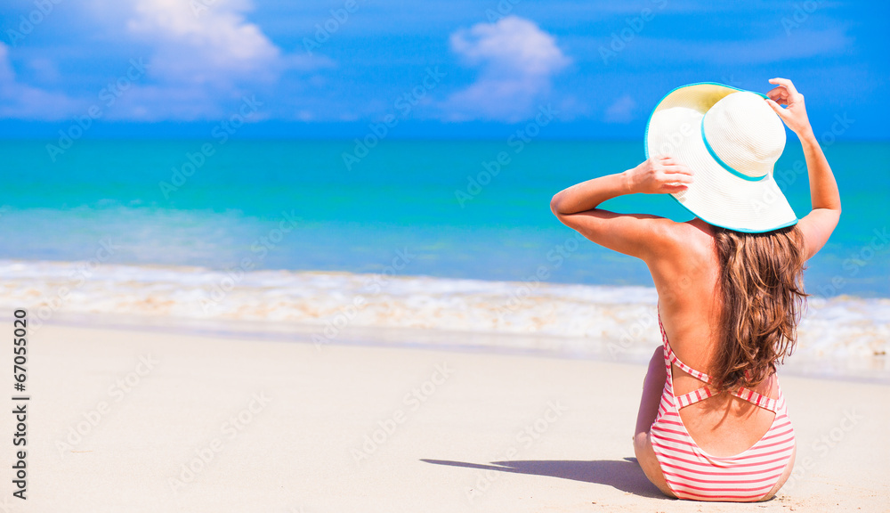 beautiful young woman in swim suit and straw hat sitting at beautiful young woman in swim suit and straw hat sitting at