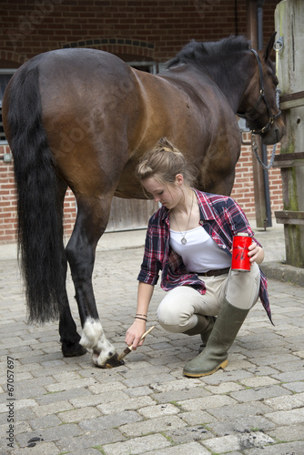Young female rider preparing her pony in the stable yard