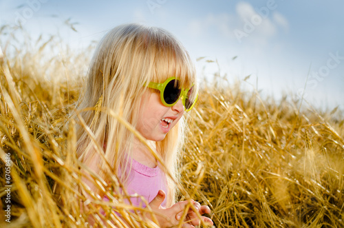 Cute little girl wearing sunglasses, in a warm day
