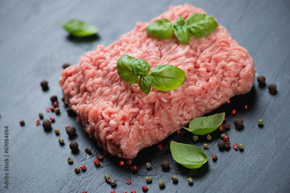 Raw ground meat with spices over black wooden background Raw ground meat with spices over black wooden background