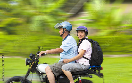 senior couple driving motorcycle with dynamic background