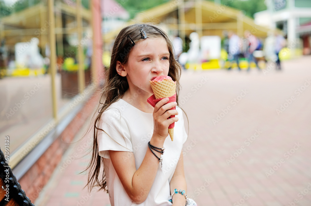 Cute brunette kid girl eating strawberry ice cream in the city Cute brunette kid girl eating strawberry ice cream in the city