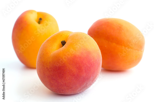 Three beautiful ripe apricots arranged on white.