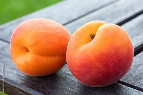 Fotografia Ripe apricots arranged on a table, out of focus grass behind.