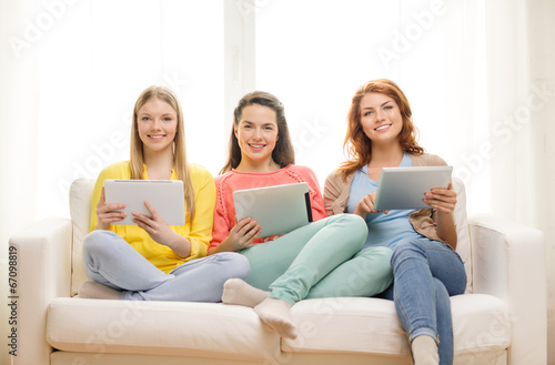 three smiling teenage girls with tablet pc at home